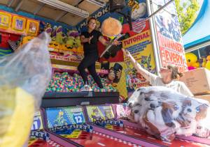 Meagan Scheeprs, left, reaches out to catch a stuffed animal thrown by Rachelle Keiser at one of their booths at the Evergreen State Fair on Wednesday, Aug. 20, 2025, in Monroe, Washington. (Olivia Vanni / The Herald)