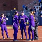 Washington Huskies softball player Alexis DeBoer (16) meets with teammates in the pitching circle at Husky Softball Stadium in Seattle during a game against Michigan on March 22. (Photo courtesy of Washington Athletics)