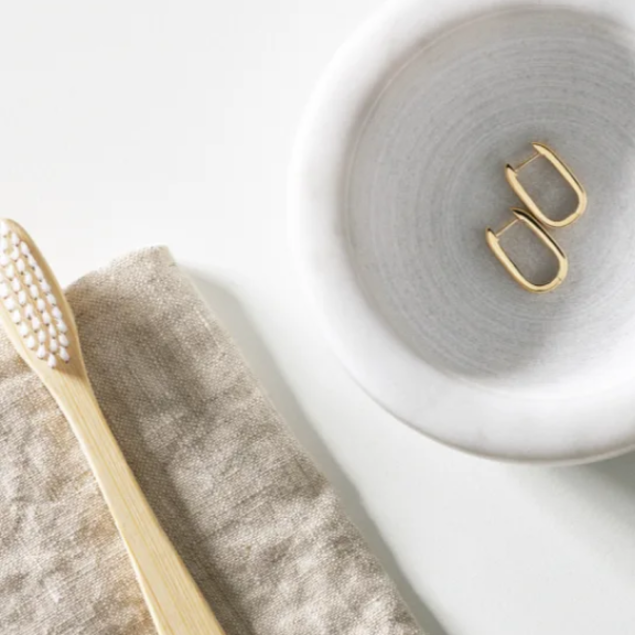 gold hoop earrings in soap dish next to toothbrush